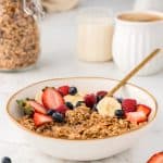 bowl full of granola, berries, and milk.