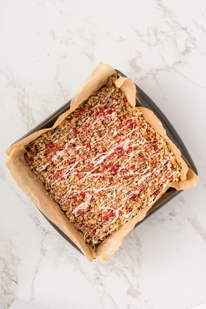 overhead of granola bars in a parchment lined square pan.