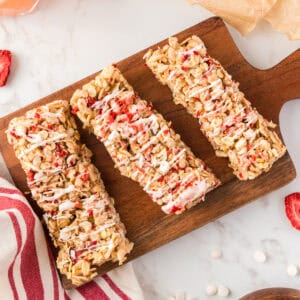 Three granola strawberry bars on a wood board.