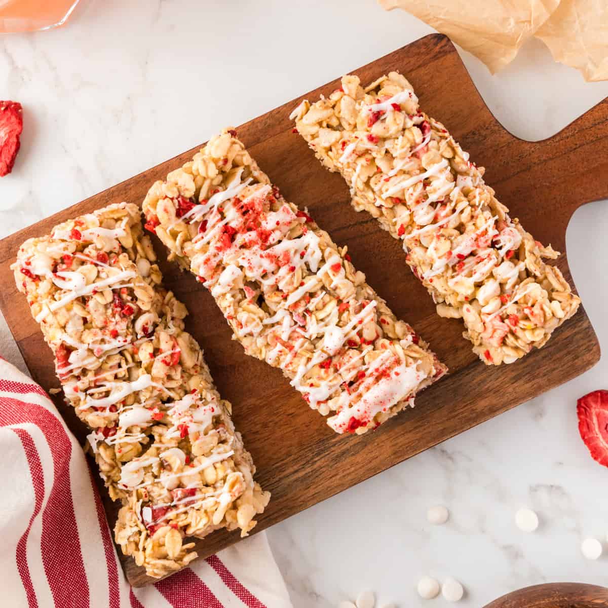 Three granola strawberry bars on a wood board.
