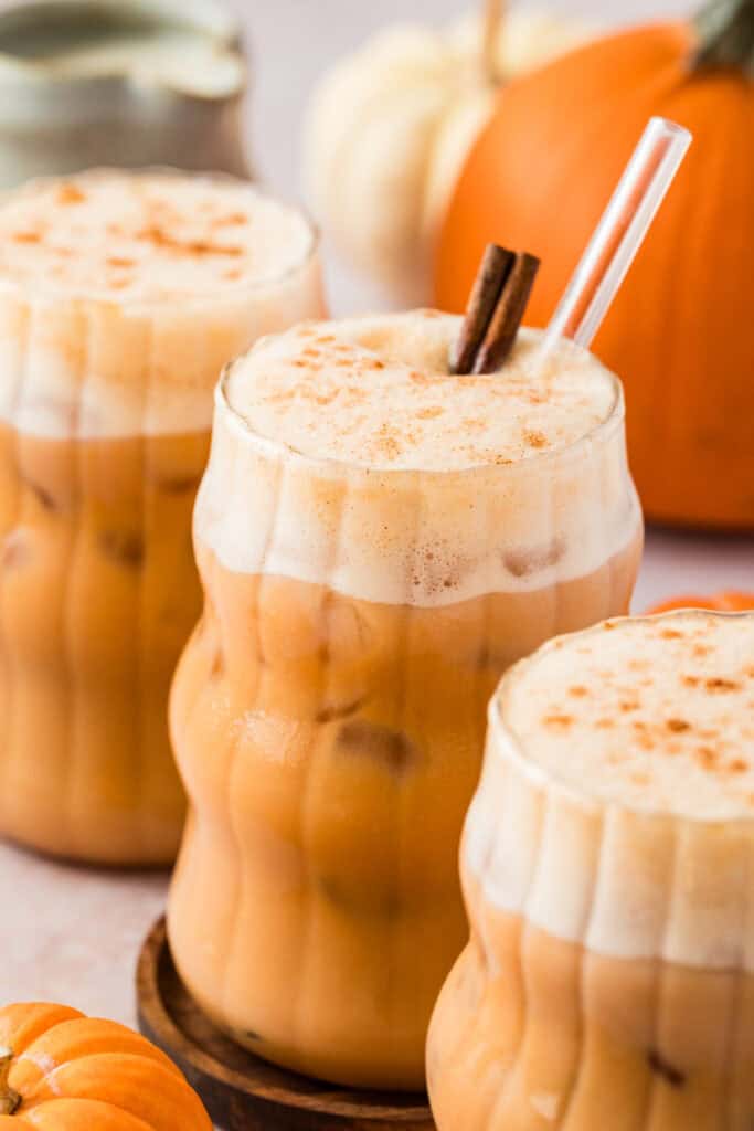 Three glass cups full of iced pumpkin spice chai tea latte.