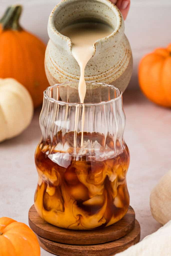 Someone pouring milk into chai tea concentrate.