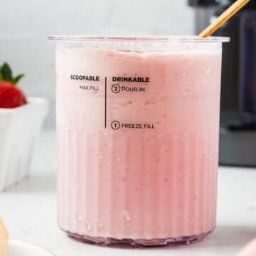 Straight on shot of smoothie bowl in the creami container after being processed, with creami machine in the background.