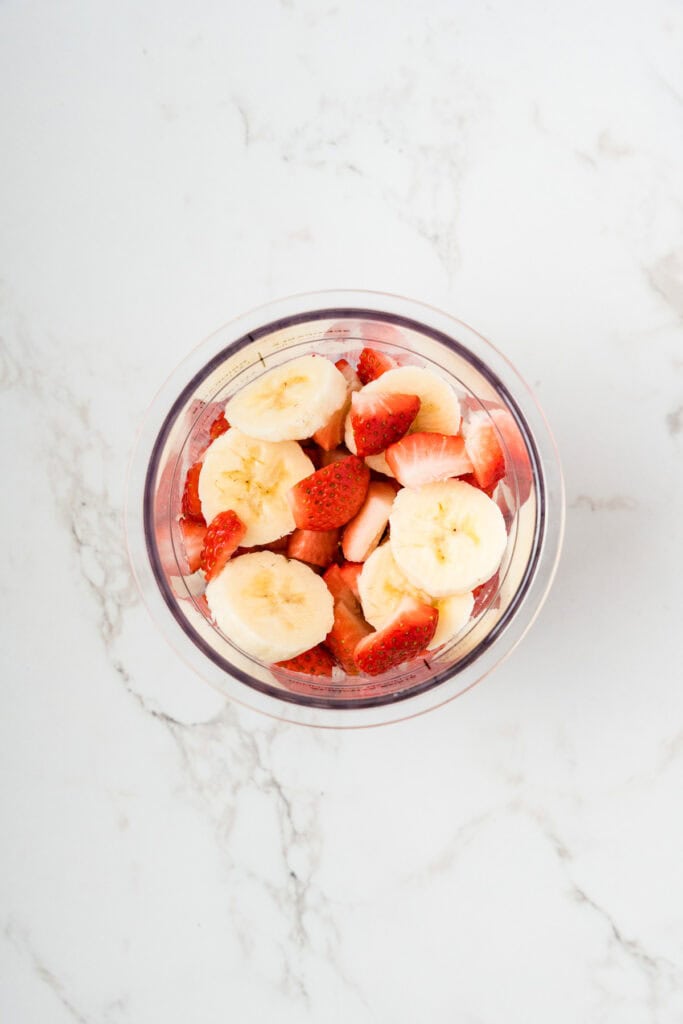 Overhead shot of strawberries and bananas in creami container.