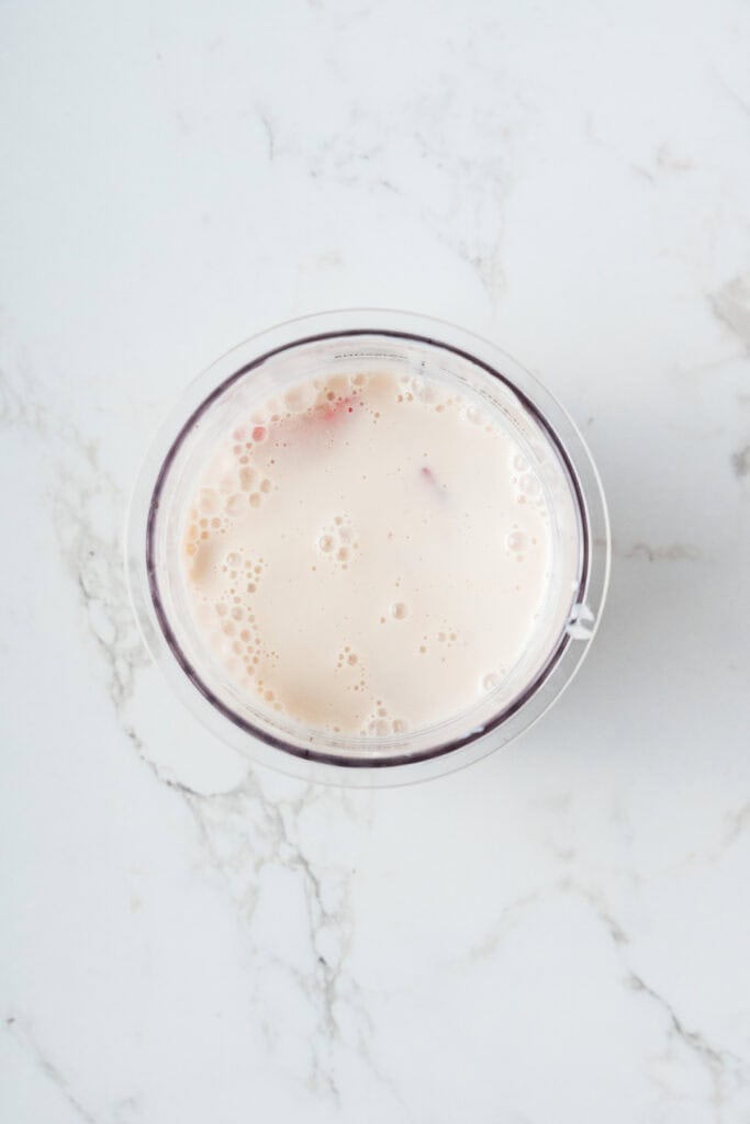 Overhead shot of almond milk covering the fruit in the creami container.