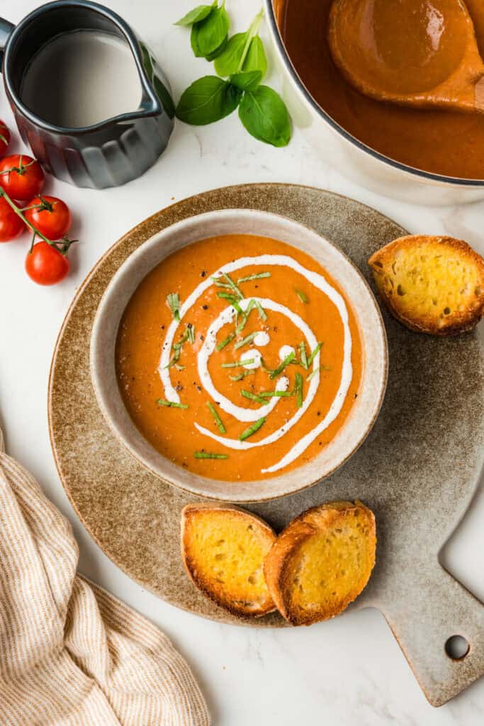 overhead photo of soup in a bowl with creamer, toast, and put of soup surrounding it.